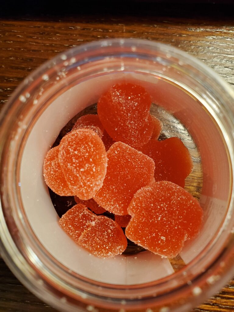 Image of gummies inside DOTZ photo on right. They are red and in the shape of a mushroom.