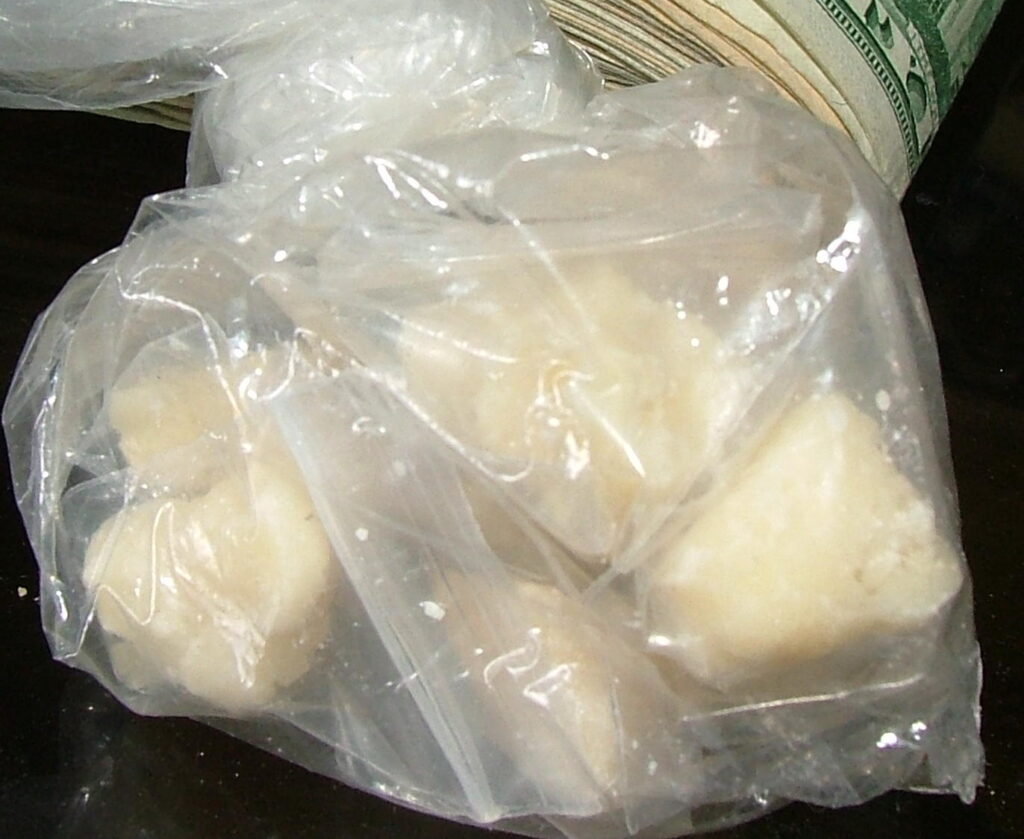 Image is of bag of off white chunks of what is crack cocaine. Behind the bag you can see a wad of money.