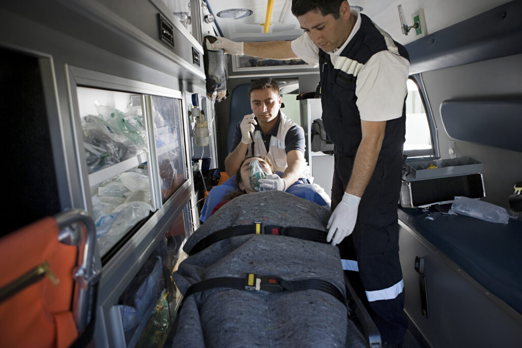 Emergency responders wearing gloves tending to a patient in an ambulance.