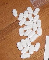 White pills on a wood table.