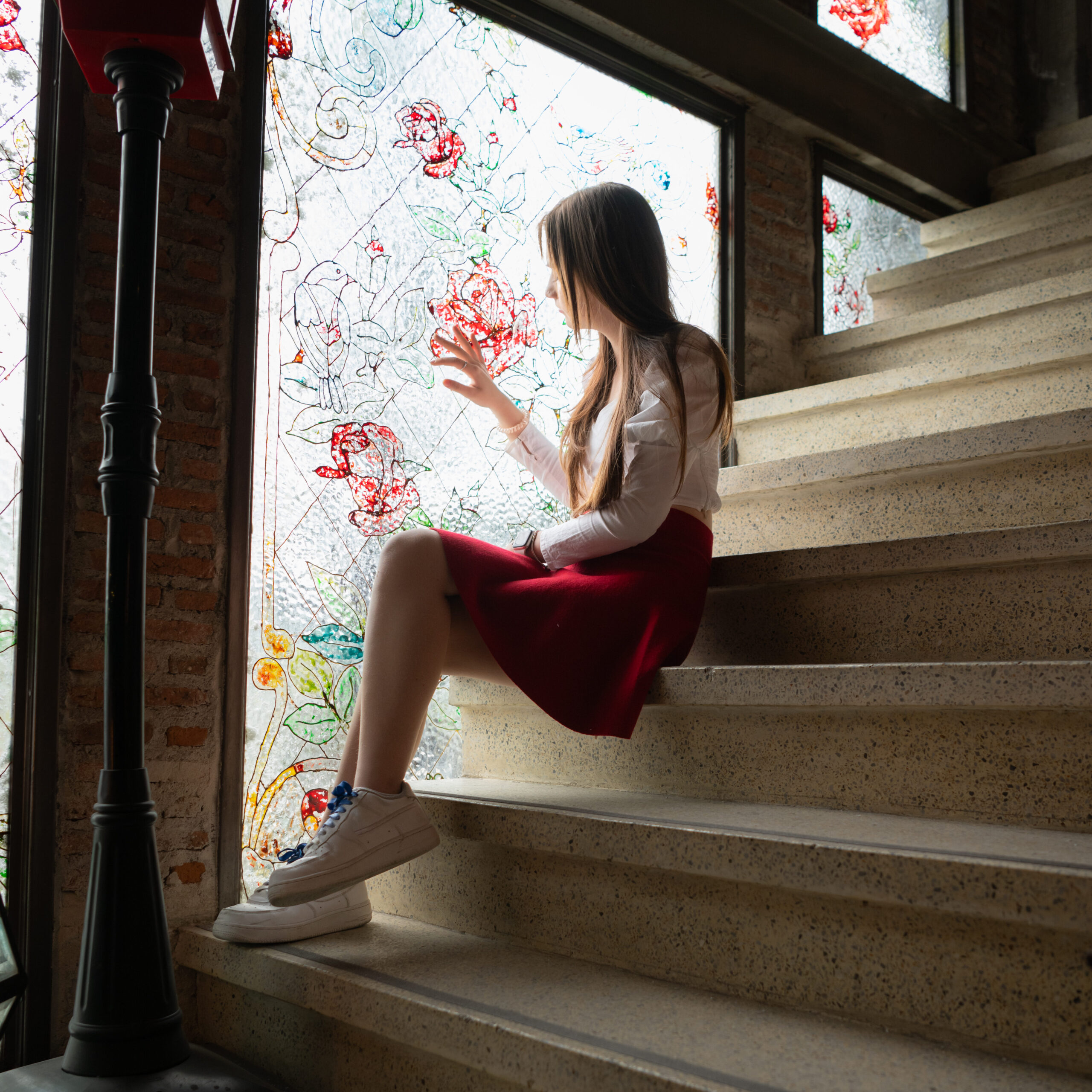 Girl with a red skirt looks out a stained glass window. The scene is dark and represents the depression caused by Fentanyl use.