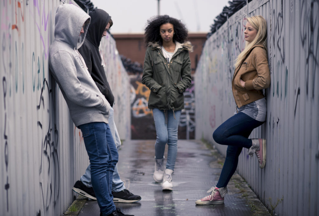 Teenagers hanging out in the kind of place where a drug deal might go down. Graffiti marks the walls.